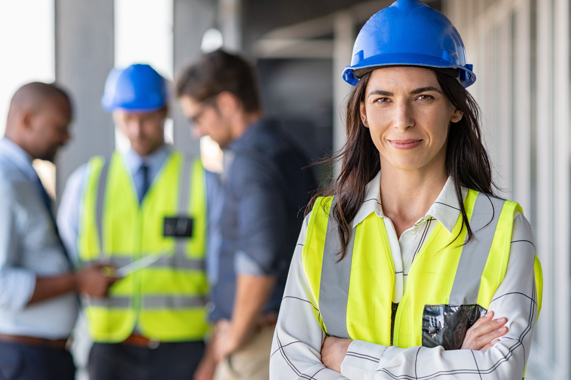 A woman in yellow vest and hard hat holding a cell phone.